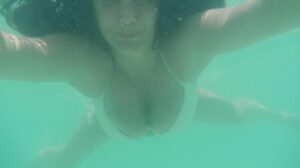 brunette à lunettes exhibe son corps en vacances à la plage